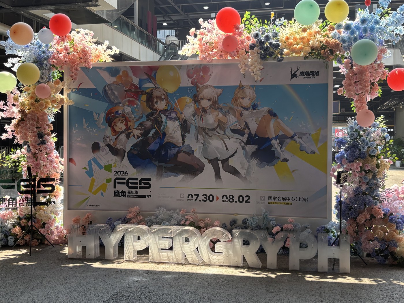 明日方舟 2026 嘉年华的主视觉打卡板，气球和花艺围着 HYPERGRYPH 立体字